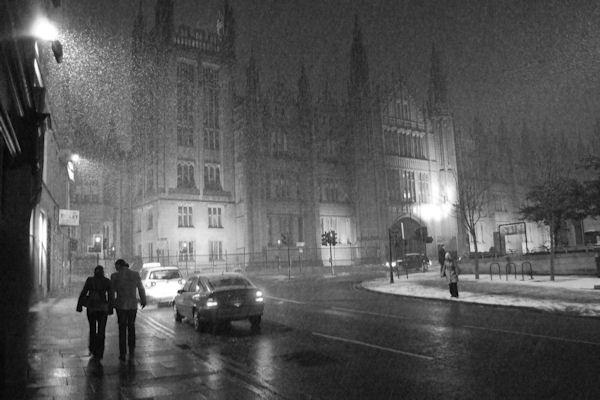 Two passers-by walking in the snow, Marischal College, Aberdeen, Scotland.